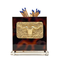Load image into Gallery viewer, Tortoiseshell desk organizer with gold bull emblem and blue matches on a white background