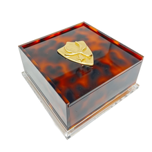 Load image into Gallery viewer, Tortoiseshell-patterned jewelry box with a gold emblem on a white background