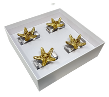 Load image into Gallery viewer, Set of four gold starfish napkin rings in a white box