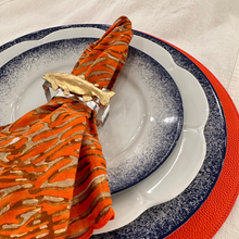 Load image into Gallery viewer, Plated dish with orange tiger-patterned napkin and gold napkin holder on a white tablecloth.