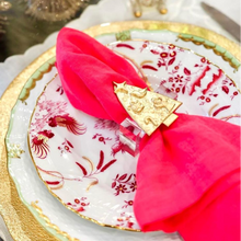 Load image into Gallery viewer, A golden napkin ring with a Christmas tree design, placed on a white plate with a red and white patterned napkin.