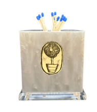 Load image into Gallery viewer, A clear acrylic match striker with a gold topiary tree design on the front, filled with matches, on a dark background.