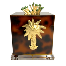 Load image into Gallery viewer, A clear acrylic match striker with a gold palm tree design on the front, filled with matches, on a white background.