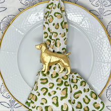 Load image into Gallery viewer, A napkin ring featuring a green and white spaniel dog design on a white napkin, presented on a plate with a blue floral pattern.
