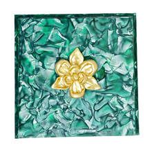 Load image into Gallery viewer, Gold flower-shaped object on a green textured background
