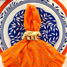 Load image into Gallery viewer, Orange napkin with gold bear napkin ring on a decorative plate
