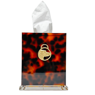 Tortoiseshell patterned tissue box with a gold emblem on a white background