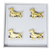 Load image into Gallery viewer, Set of four gold dog-shaped napkin rings in a box on a white background
